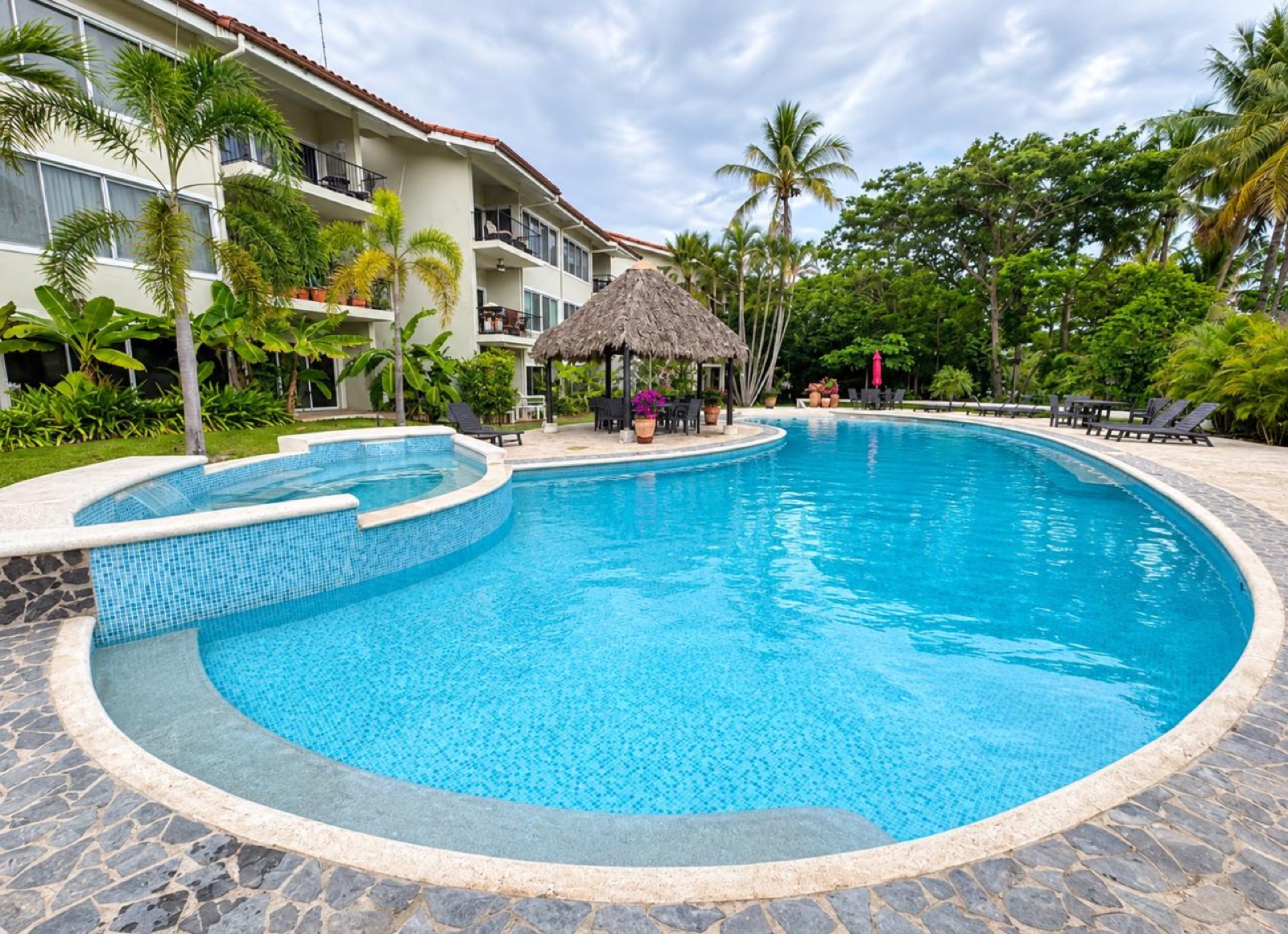 Piscina tropical compartida en Bahia Langosta, con palmeras y rancho